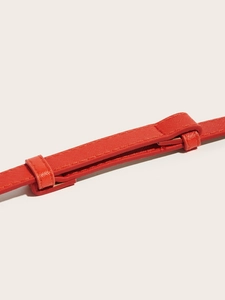 Macro shot of orange Saffiano leather belt detail with adjustable buckle attachment