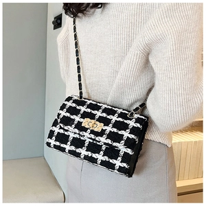 Detail of the black and white tweed texture and gold metal clasp on a chain bag