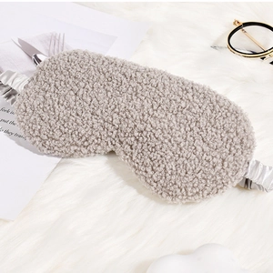 Detail of soft gray plush sleep mask with elastic silk-feel strap on white fur background