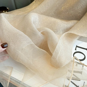 Detailed texture of gold shimmer silk scarf with light transparent fabric on a magazine