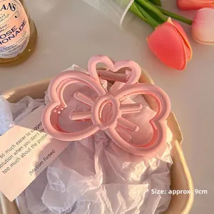 Macro detail of a 9cm pink matte bow hair claw clip with heart motif in a stylish layout