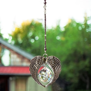 Crystal angel wings suncatcher with purple beads hanging in a garden setting