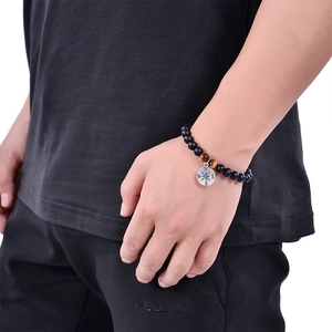 Macro shot of men's matte black beads bracelet with compass charm and tiger eye stones