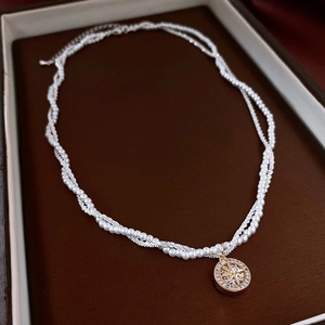 Dettaglio della collana di perle a strati con un ciondolo a medaglione a stella d'oro