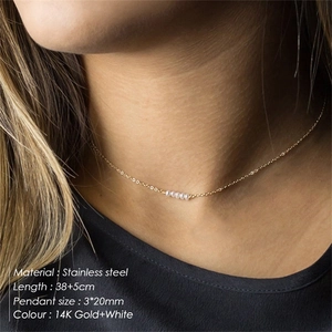 Detailed view of layered 14K gold stainless steel necklace with white pearls on a model