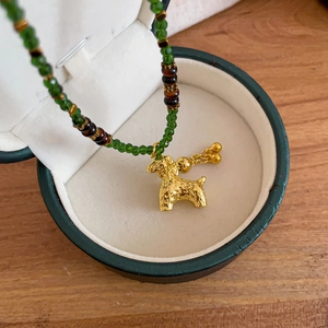 Detail of gold-plated puppy pendant with green crystal beads in a gift box