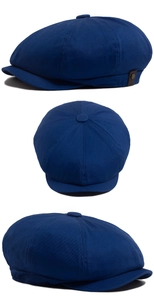 Detailed view of navy newsboy cap featuring cotton twill texture and leather side label