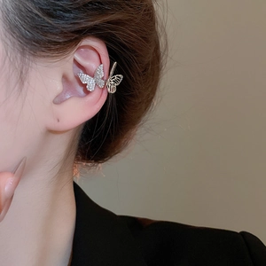 Macro detail of a silver butterfly ear cuff with sparkling zircon and hollow design