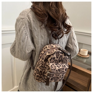 Rear view of model wearing a mini leopard print backpack with double zipper closure