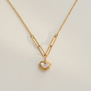 Macro shot of the 18k gold heart pendant with white shell inlay and paperclip chain