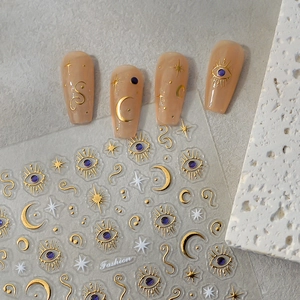 Détail des stickers d'ongles 3D dorés aux motifs célestes de lune et d'étoiles