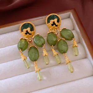 Vintage gold tassel earrings with dark green stones and droplets on white velvet