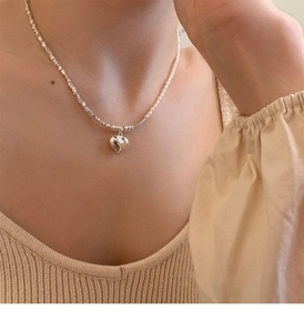 Detail of a pearl and silver heart pendant necklace worn on a collarbone for women