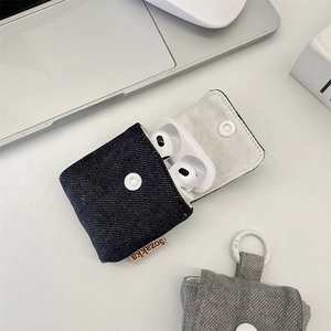 Detailed close-up of mini denim earphone cases with snap closure on a white desk