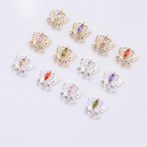 Macro shot of 12 mixed-color marquise zircon crown nail charms on reflective gray surface