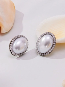 Macro view of oval shell pearl earrings with shimmering pavé zircon and seashell decor