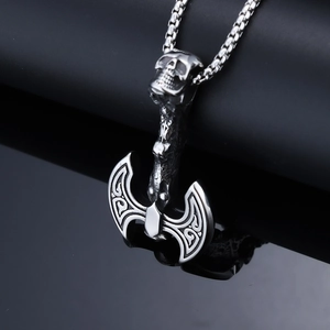 Macro shot of Viking battle axe pendant with skull detail on polished black reflective surface