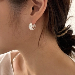 Close-up of minimalist silver pearl hoop earrings worn by a model in a side view