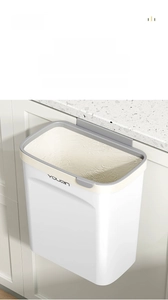 Detail of white wall-mounted kitchen trash can with a grey lid ring on a cabinet