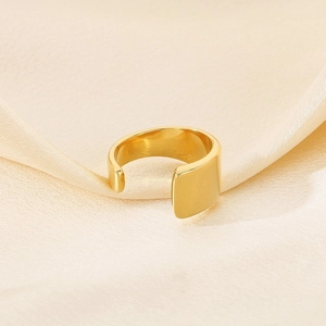 Close-up of minimalist gold plated adjustable ring on elegant beige silk fabric
