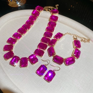Lustrous gold jewelry set with magenta rectangular stones on a display tray