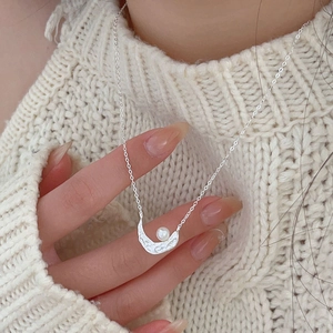 Detailed close-up of crescent moon pearl necklace on 925 silver chain worn by a model