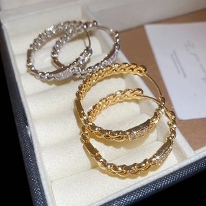 Detail of 18k gold and silver plated twisted hoop earrings with zircon pavé accents