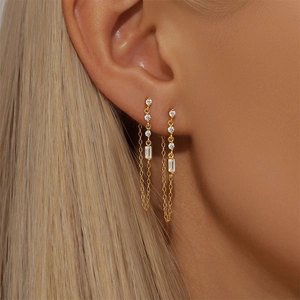 Detail of gold floral heart earrings with zircon tassel on a model with double piercings