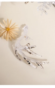 Clear acrylic reindeer antler ornament with gold and silver glitter on beige leather