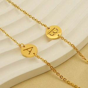 Close-up of golden stainless steel necklace featuring hollow round A and B letter pendants