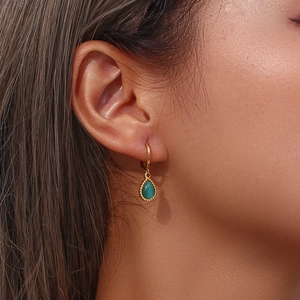 Detail of gold drop earrings featuring green waterdrop cat's eye stones with beaded edges