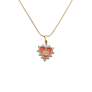 Détail du collier cœur doré avec pierre rouge et motif œil en vue macro