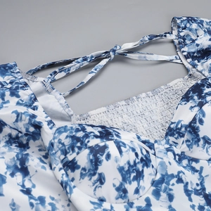 Détail du haut à fleurs bleu et blanc avec smocks élastiques et fines bretelles