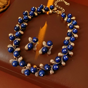 Detailed view of vintage gold necklace and blue gemstone earrings on brown leather