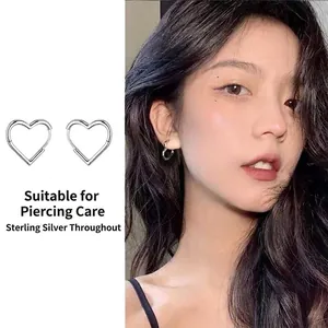 Close-up of heart-shaped sterling silver hoop earrings worn by an Asian model