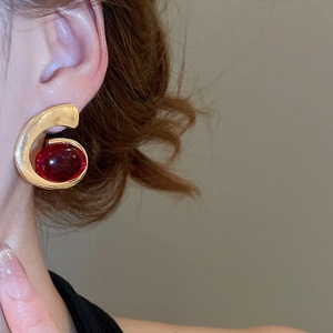 Macro shot of gold oval resin earrings with vintage red stone detail for women