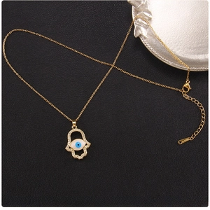 Detailed close-up of gold titanium Hamsa Hand pendant with Evil Eye and zircon accents