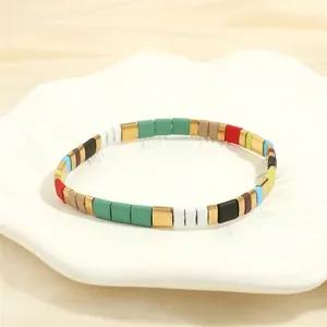 Close-up of colorful enamel tila tile bracelets on a white scalloped decorative tray
