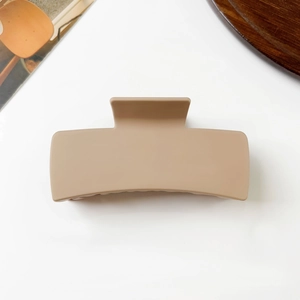 Detailed close-up of a matte beige square hair claw clip on a minimalist white surface