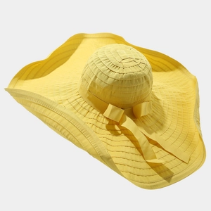 Detail of the yellow sun hat with large wavy brim and elegant ribbon bow decoration