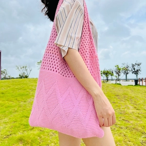 Detailed view of pink knitted tote bag with diamond cutout patterns in outdoor setting