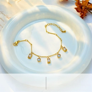 Detailed shot of a gold titanium chain bracelet featuring five zircon charms on a plate