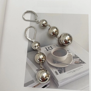 Detail showing gradient silver metal triple ball drop earrings on magazine background