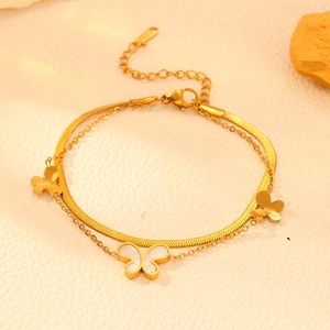Detail of gold layered stainless steel bracelet featuring butterfly charms and shell inlay