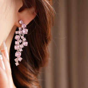 Close-up of elegant pink gemstone drop earrings featuring a dangling tassel design on model