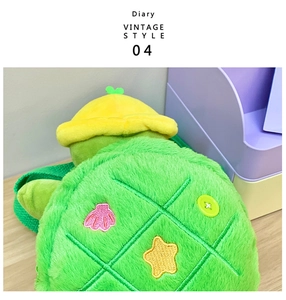 Detailed close-up of green plush turtle shell bag with colorful star and shell embroidery