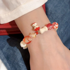 Close-up of ceramic beaded bracelet featuring a red apple pendant and bone-shaped charms