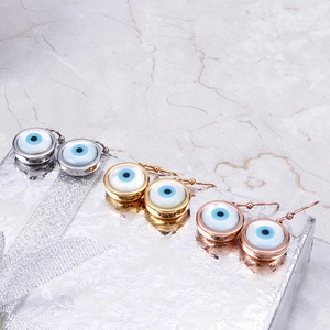 Three pairs of evil eye earrings in gold, silver, and rose gold on a gift box
