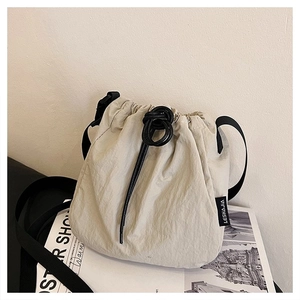 Detail of water-resistant nylon bucket bag featuring drawstring closure and side woven label