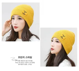 Detail of yellow ribbed knit beanie featuring Moment of Ambitions square patch